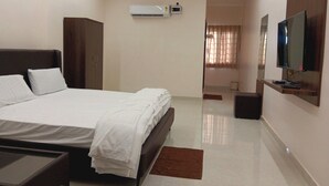 A hotel room with a bed, a TV, an air conditioning unit, and a wardrobe.