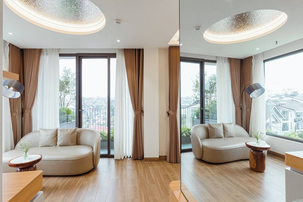 Una habitación de hotel moderna con dos sofás, una mesa redonda y un ventanal con vistas a la ciudad.