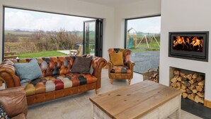 Ein modernes Wohnzimmer mit großem Fenster, Kamin, einer Ledersofa und einem Holztisch.
