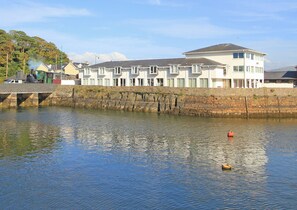 Une propriété située au bord de l’eau, avec une rangée de maisons blanches, un pont et une rivière paisible.