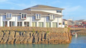 A coastal building with multiple windows and a stone wall. - Glaslyn Retreat (Porthmadog)
