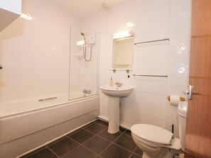 Une salle de bain moderne équipée d’une baignoire, d’un lavabo, de toilettes et d’une douche à parois de verre.