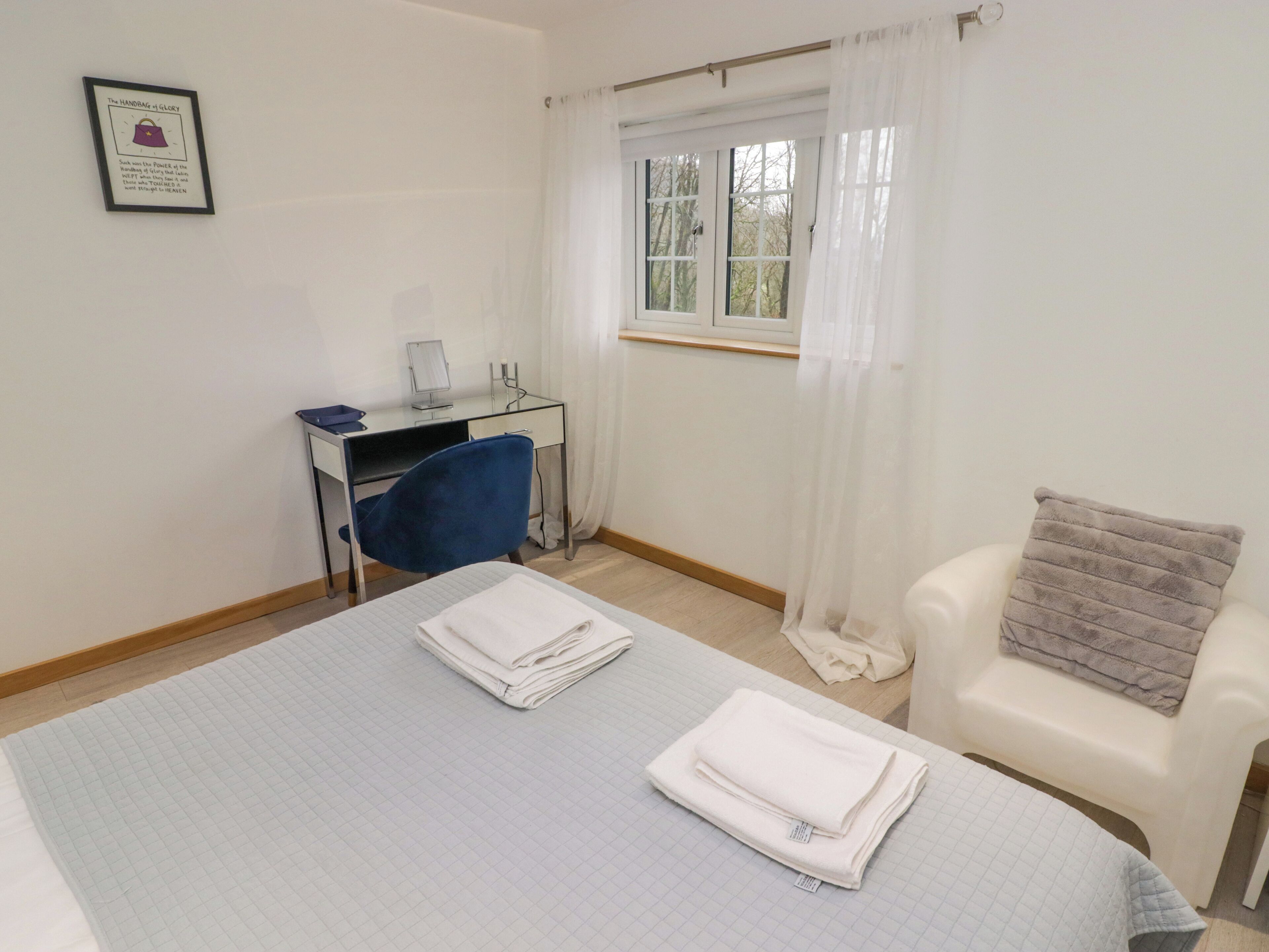 Une chambre d’hôtel avec un lit, un bureau, une chaise et une fenêtre avec des rideaux.