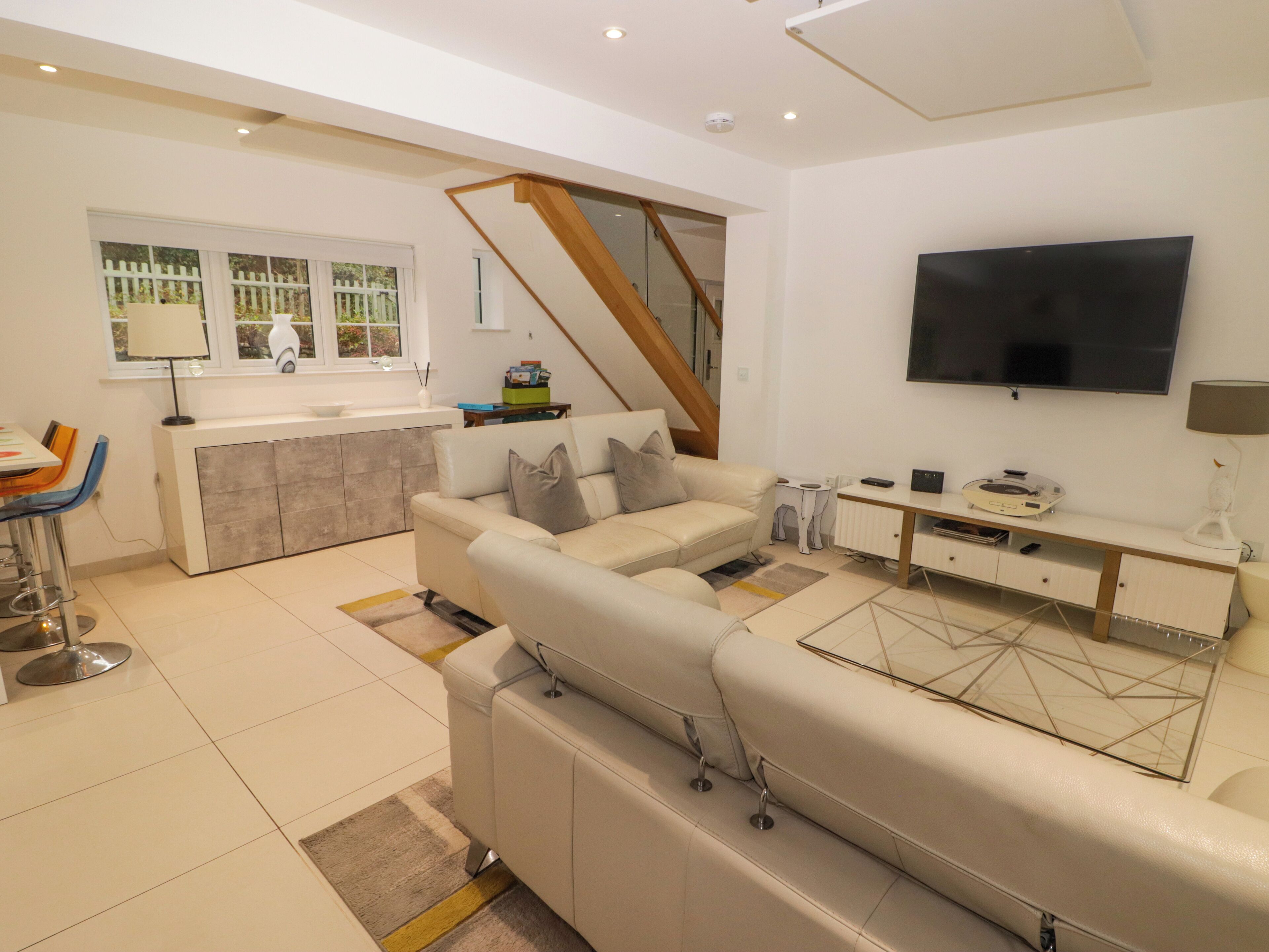 Una sala moderna con sofá, televisión y una zona de cocina con ventana.