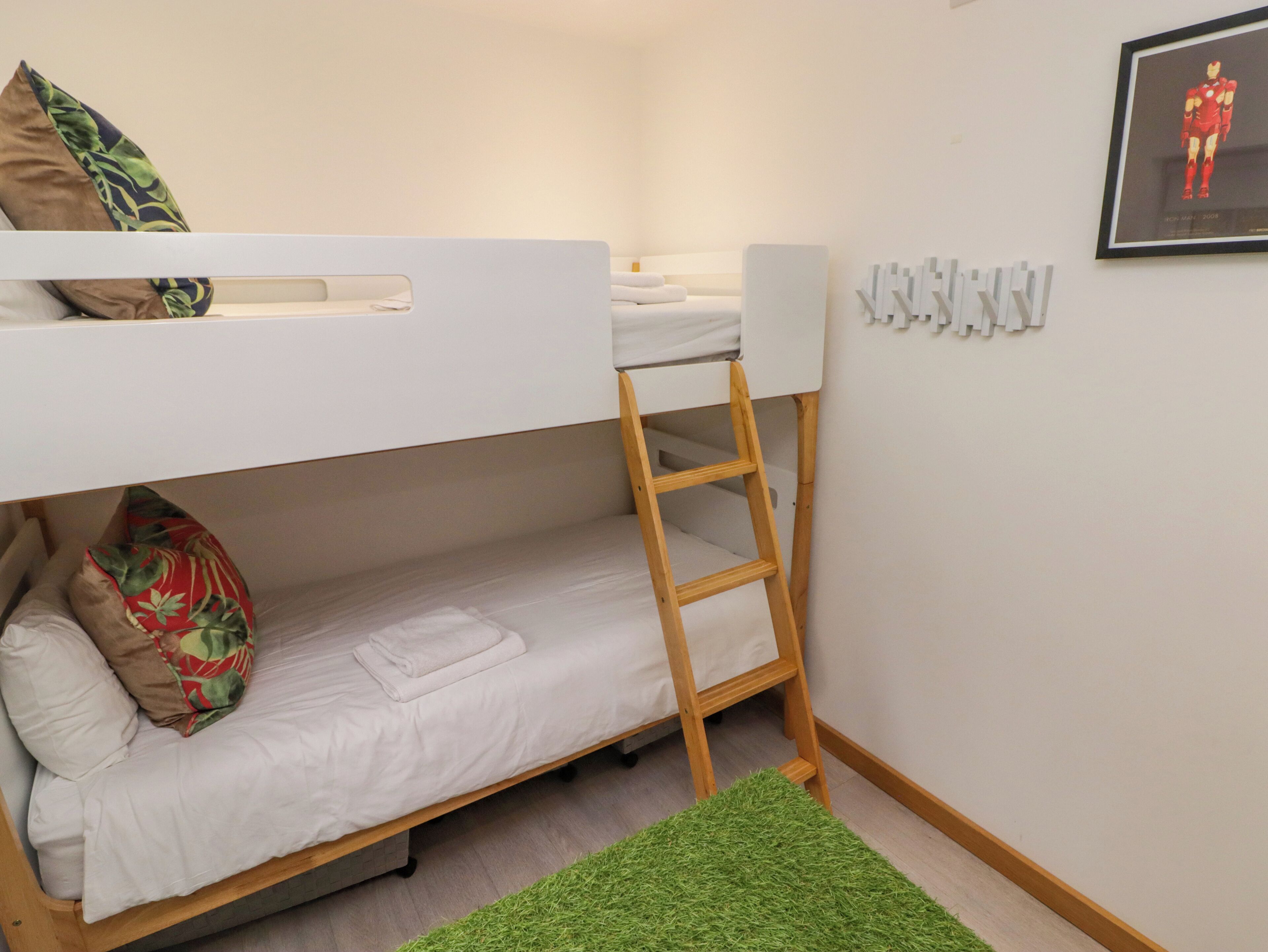 Una cama individual superpuesta con una escalera, una alfombra verde y un cuadro en la pared.