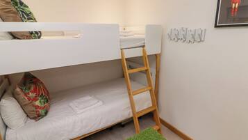Una cama individual superpuesta con una escalera, una alfombra verde y un cuadro en la pared.