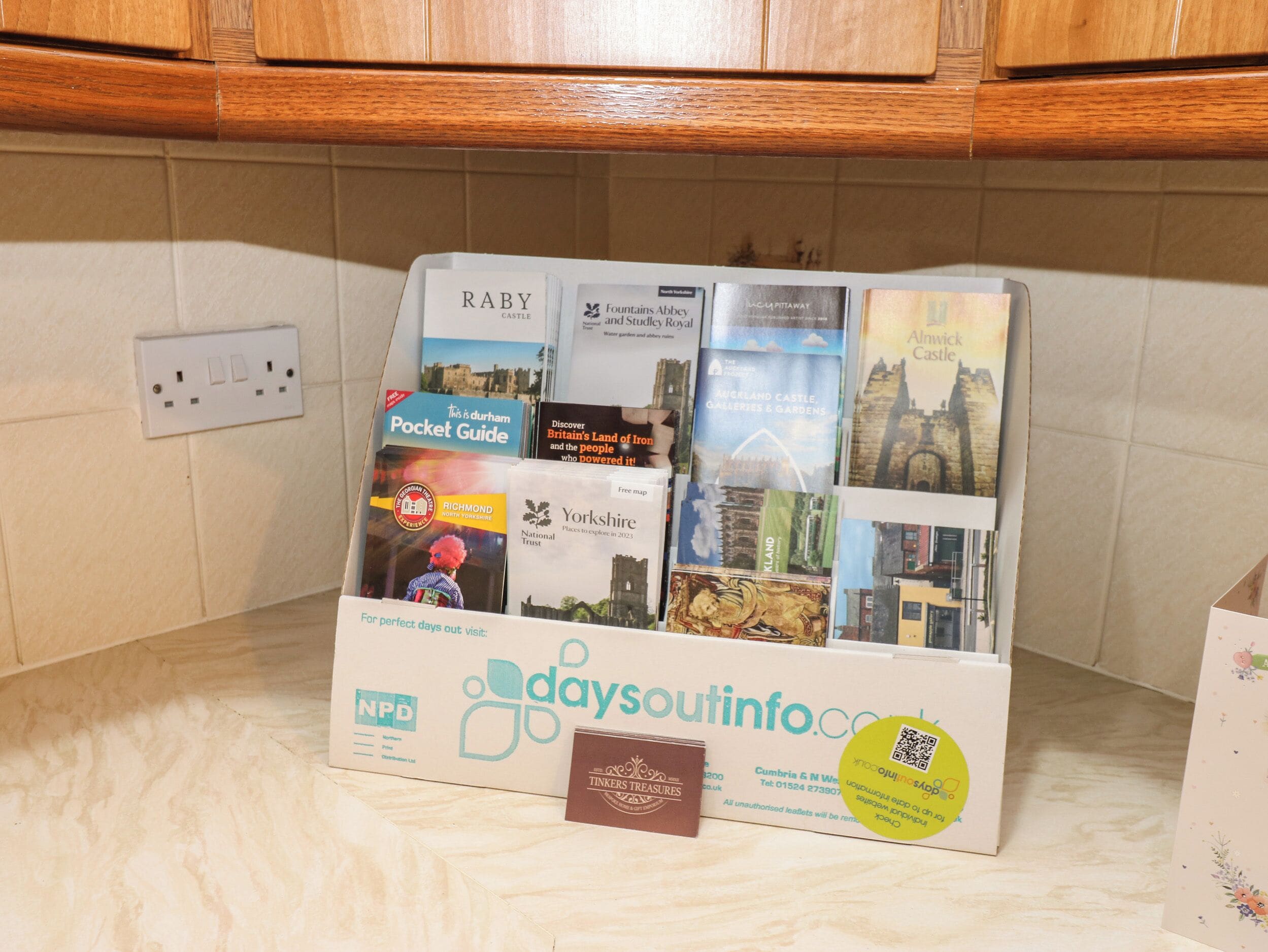 Un espositore per informazioni turistiche con diverse brochure e una tessera Tickers Treasures.