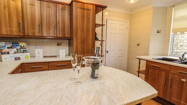 A kitchen with wooden cabinets, a marble countertop, and a sink. - The Old Assembly Rooms (Bishop Auckland)