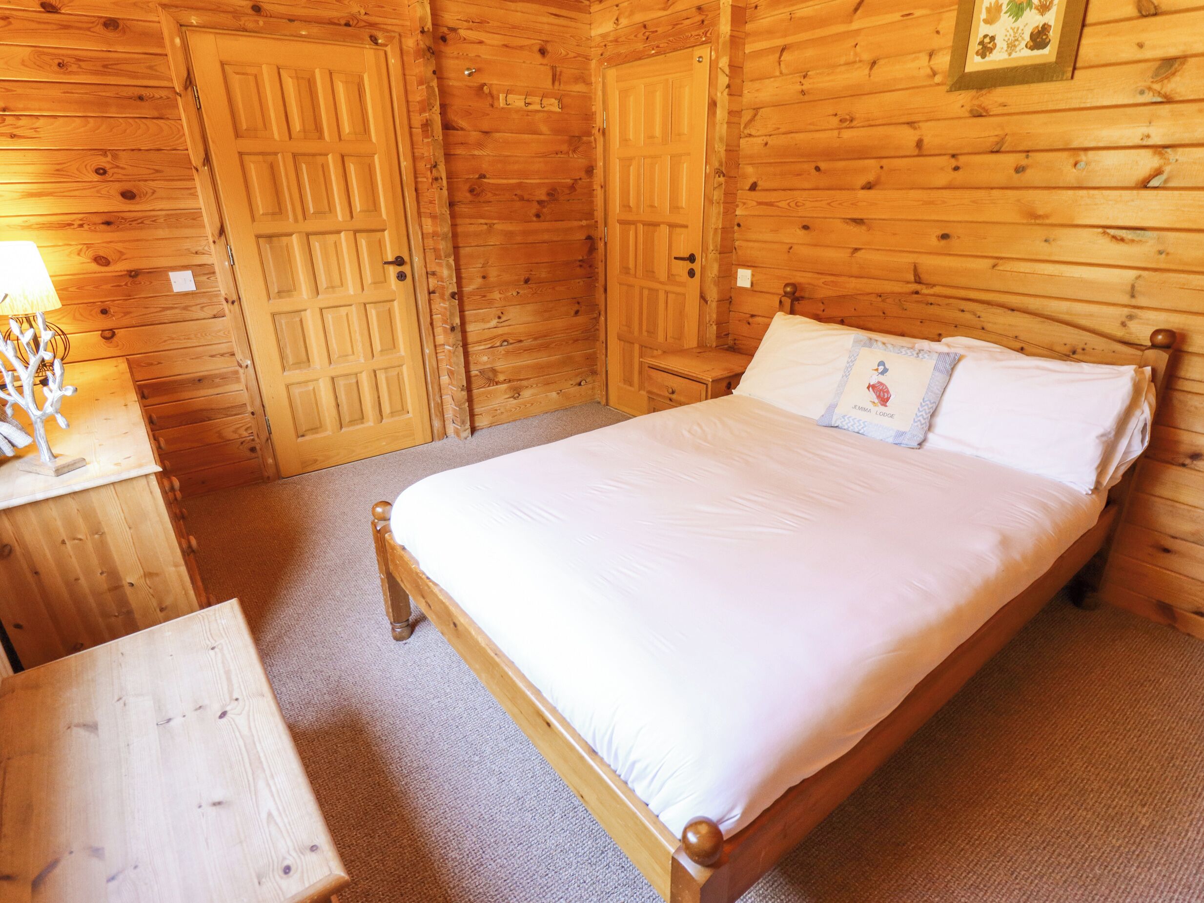 A wooden room with a bed, a nightstand, and a dresser.