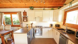 Une cuisine de taille réduite avec des meubles blancs, un îlot central, une cuisinière et un évier.