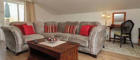 A living room with a sectional sofa, a coffee table, a desk, and a chair.