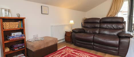 A cozy living room with a leather recliner, a wooden bookshelf, and a red patterned rug.