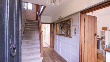 A staircase with wooden steps and a handrail, leading to a landing with a white paneled wall and a large mirror.