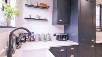 A kitchen with dark cabinets, a white countertop, and a window with a plant.