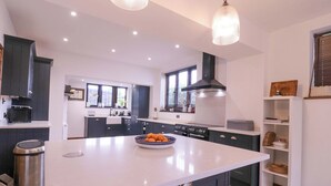Una cocina moderna con armarios oscuros, una isla grande e iluminación colgante.