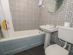 A bathroom with a bathtub, a sink, a toilet, and a shower curtain. - 56C South Snowdon Wharf (Porthmadog)