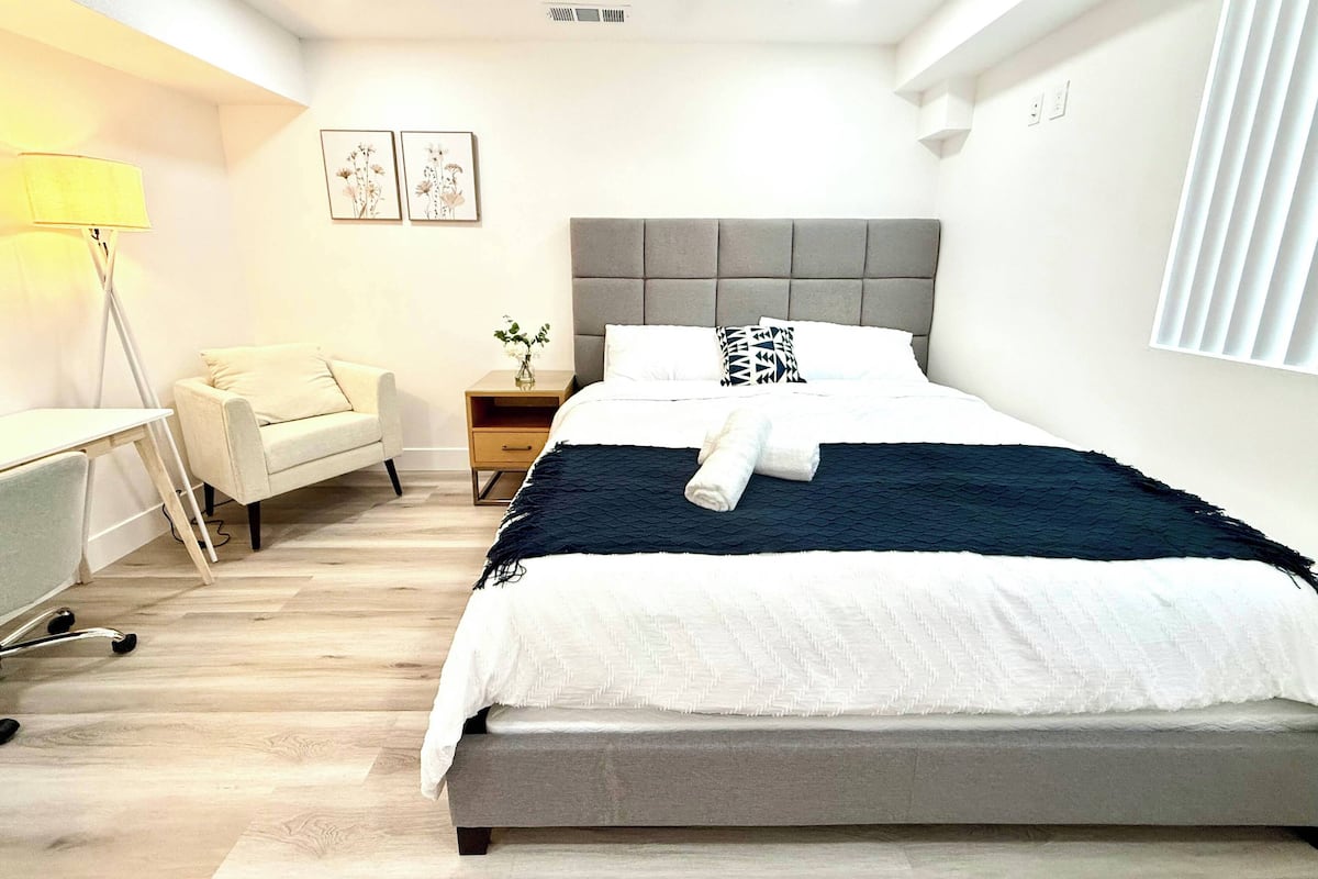 Une chambre à coucher moderne avec un lit, une table de chevet, une lampe et une chaise.