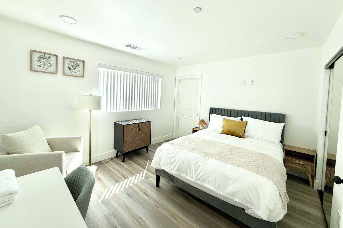 Une chambre moderne avec un grand lit, une table de chevet, une lampe et une armoire.