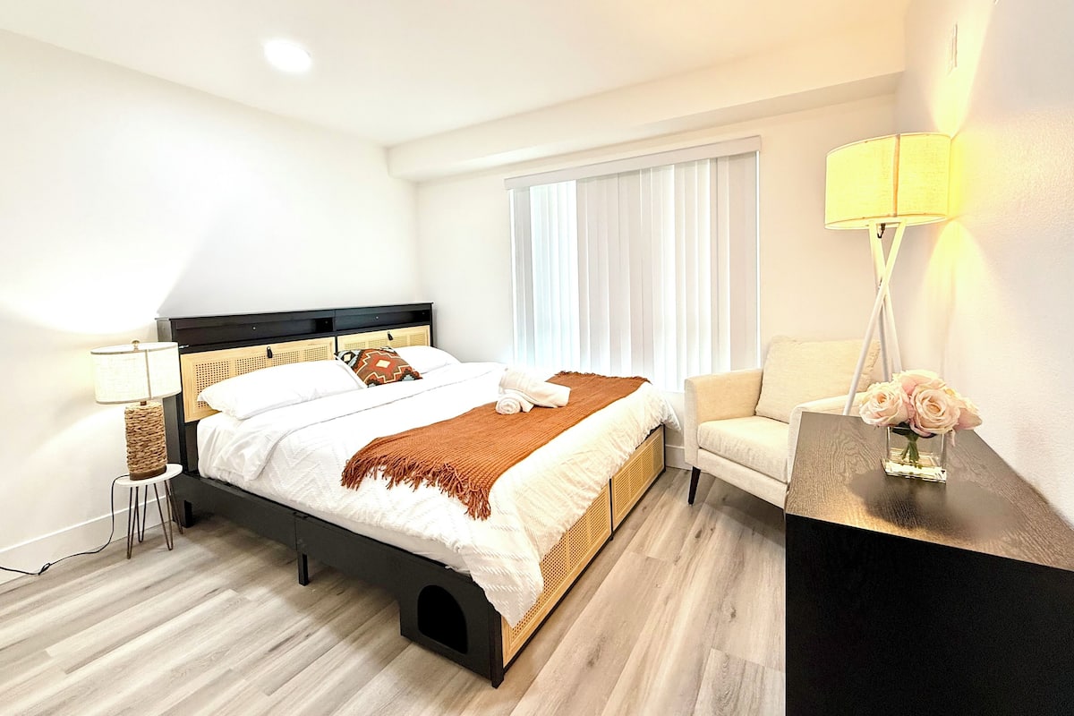Une chambre d’hôtel moderne, équipée d’un lit, d’une table de chevet, d’une lampe et d’une chaise.