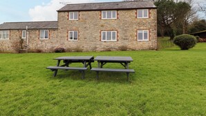 A stone building with multiple windows and a grassy lawn. - The Hayloft Cottage Apartment (Lyme Regis)