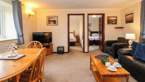 A cozy hotel room with a dining area, a living room, and a bedroom. - The Hayloft Cottage Apartment (Lyme Regis)