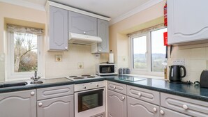 A kitchen with a stove, microwave, and sink. - The Hayloft Cottage Apartment (Lyme Regis)