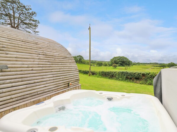 A hot tub with a view of a grassy field and a wooden structure. - Oak View (Llangadog)