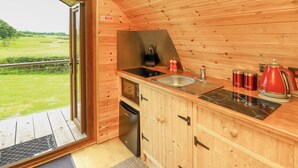 A wooden cabin kitchen with a sink, stove, and a view of the outdoors. - Oak View (Llangadog)