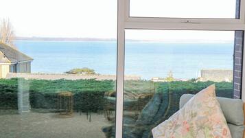 Una habitación con un amplio ventanal que ofrece vistas a una masa de agua y una costa distante.