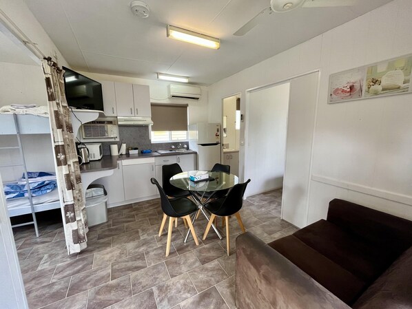 Una cocina compacta con comedor, sofá y litera.