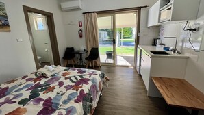 Kompakti hotellihuone, jossa on sänky, pieni keittokomero, ruokailutila ja kylpyhuone.