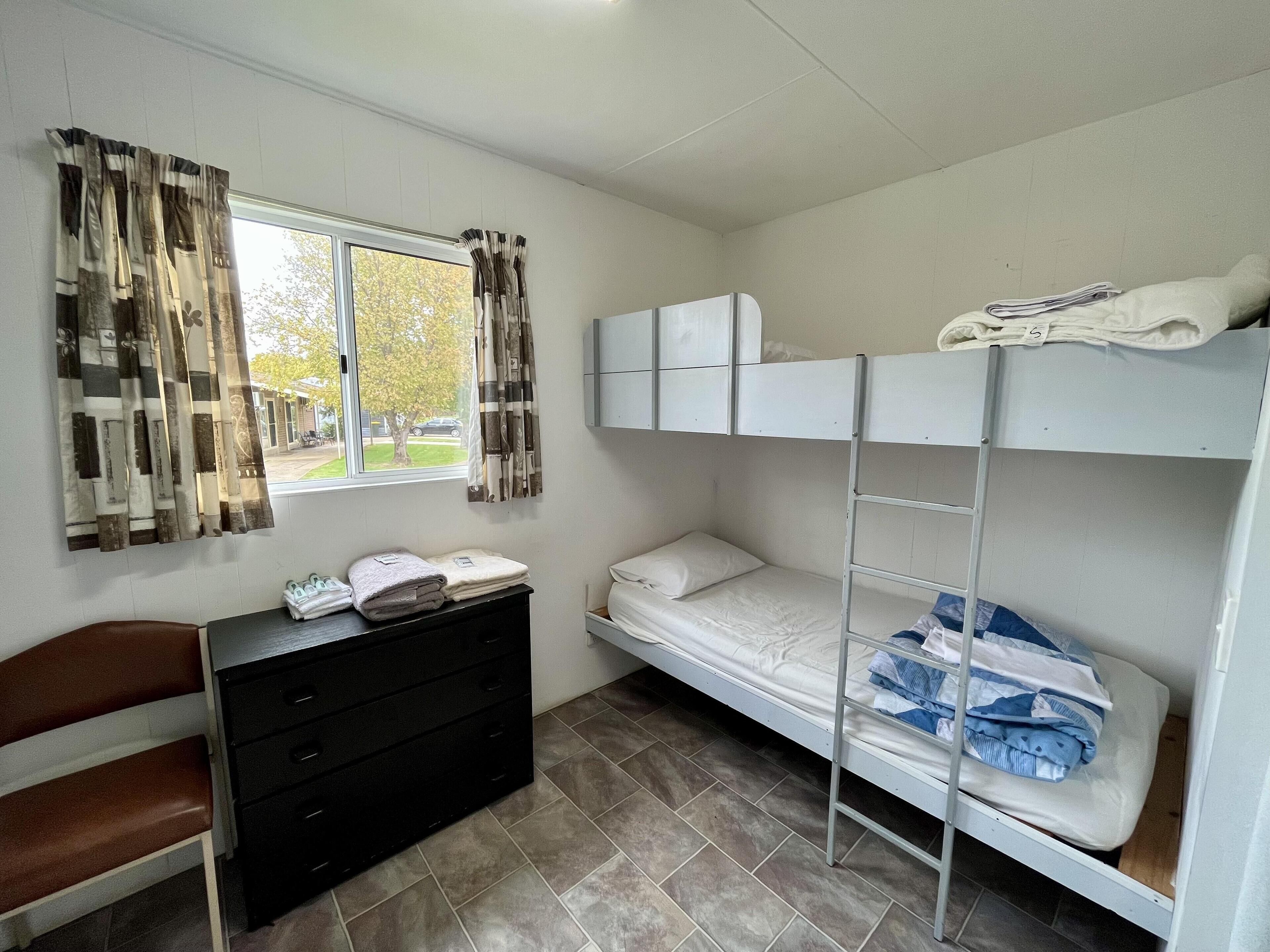 Un dormitorio con literas, un escritorio y una ventana con cortinas.