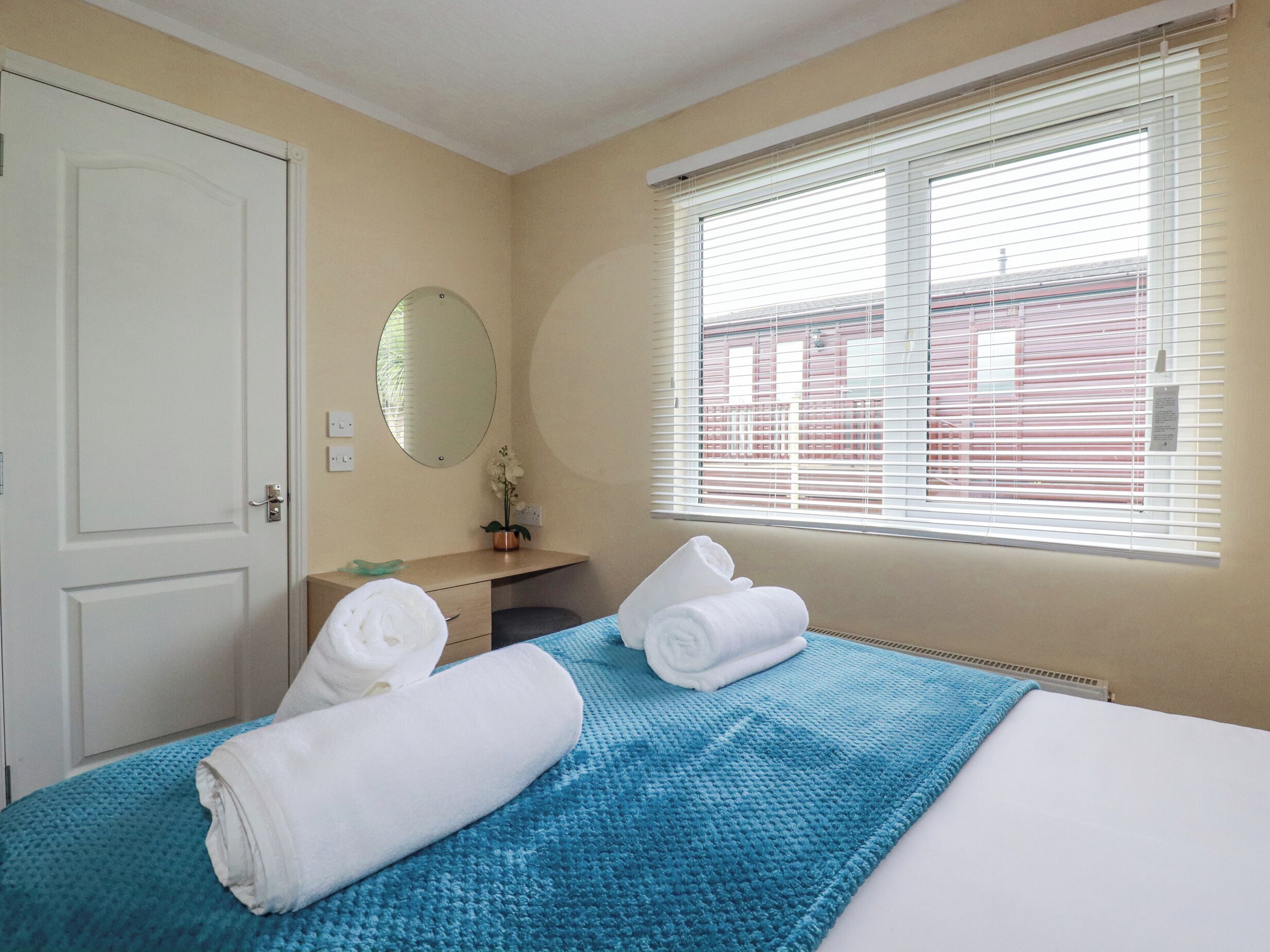 Ein Hotelzimmer mit Bett, Bad, Fenster mit Jalousien und einer Tür.