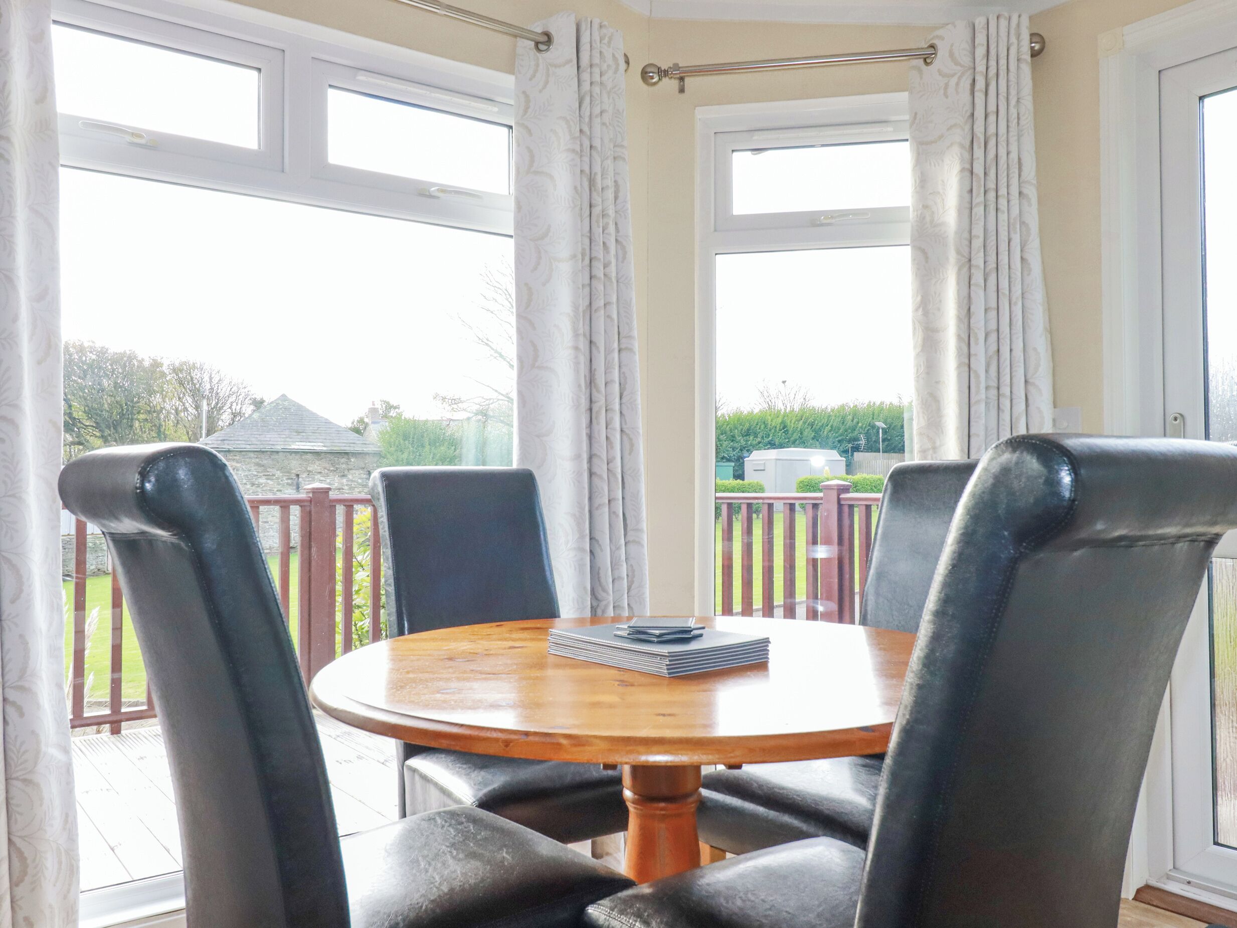 A dining area with a round wooden table and four black chairs.