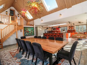 A spacious dining area with a wooden table and chairs, a staircase, and a kitchen area with a hanging light fixture. - Royal Oak House (Shaftesbury)