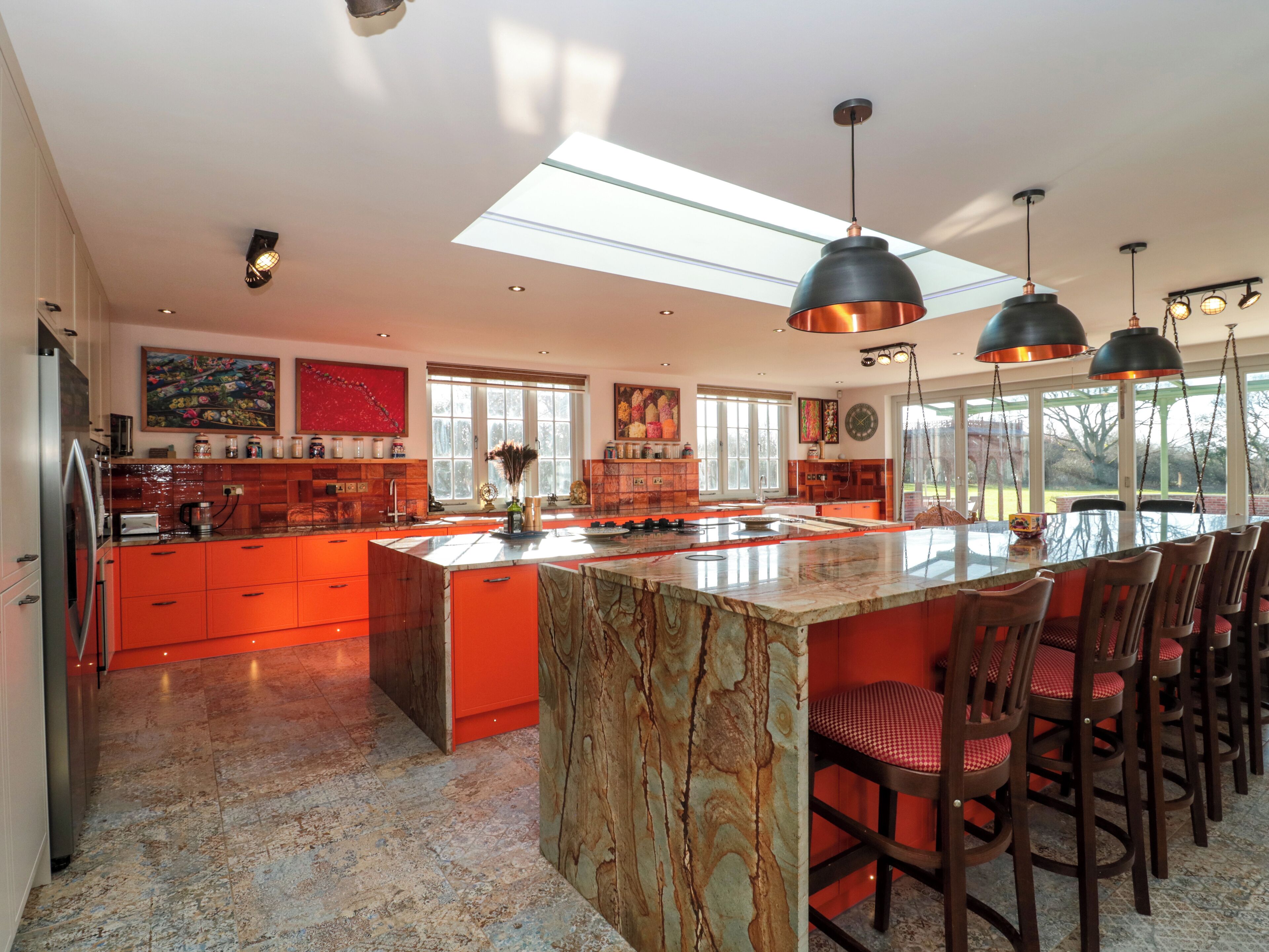 A spacious kitchen with a large island, bright pendant lights, and a view of the outdoors.