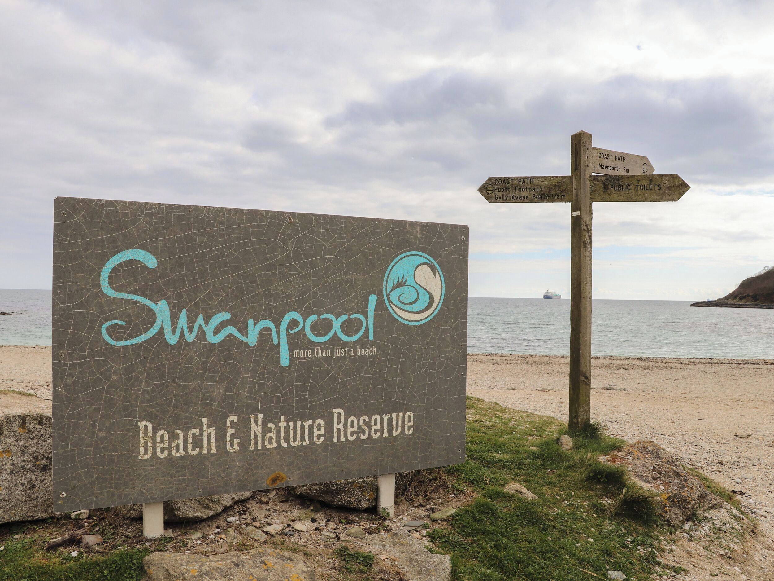 A sign for Swanpool Beach & Nature Reserve with directions to the coast path, public footpath, and public toilets.