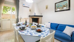 A dining area with a table set for two, a blue sofa, and a fireplace.