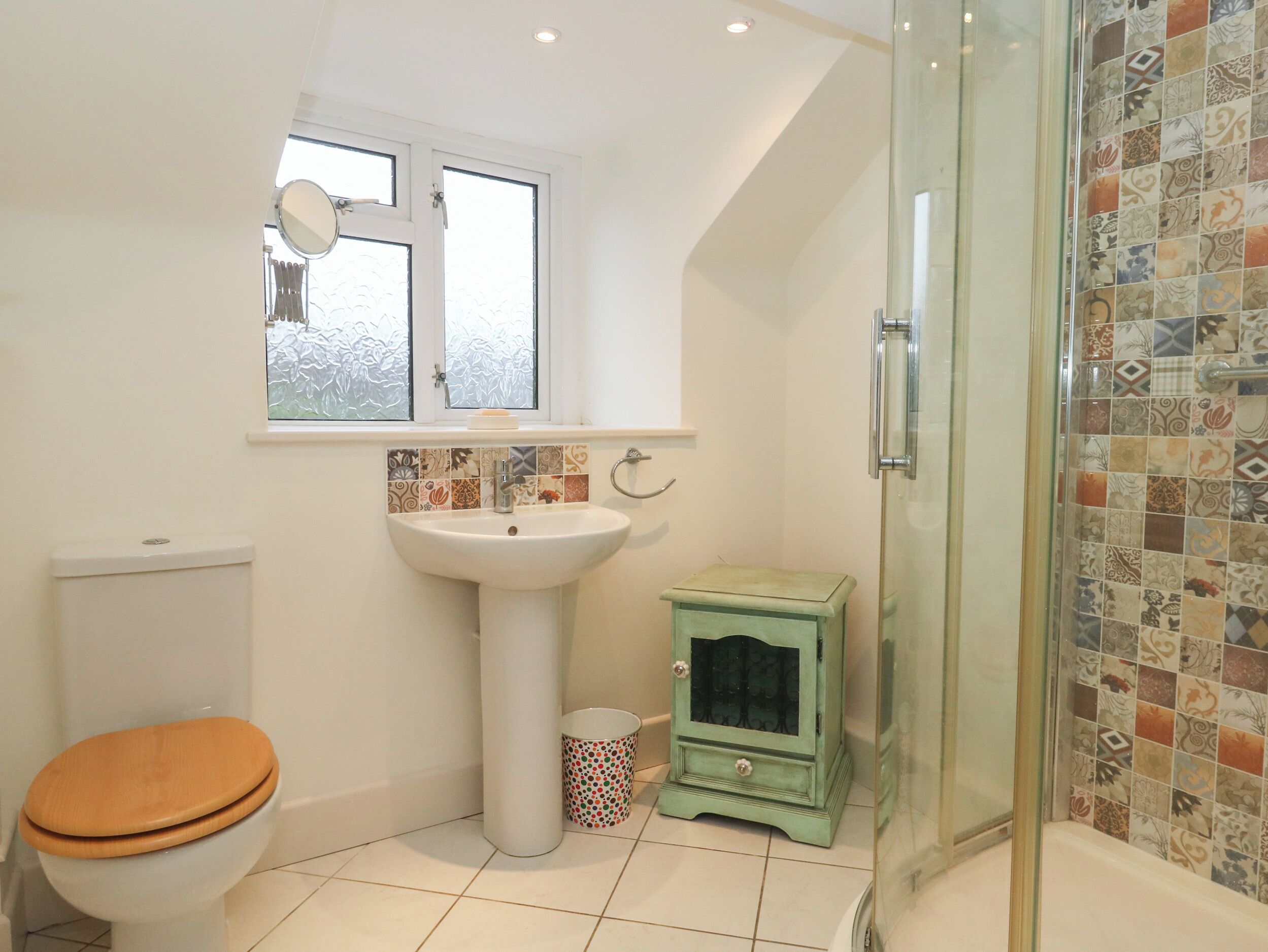 A bathroom with a toilet, sink, and glass shower enclosure.