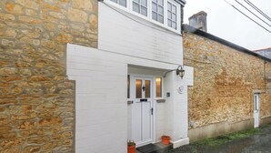 Un edificio de piedra de dos pisos con una puerta blanca y un pequeño porche.