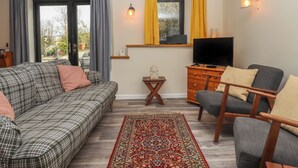A cozy living room with a sofa, armchair, TV, and a small table.