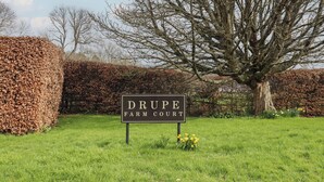 A sign for Drupe Farm Court surrounded by greenery and a large tree.