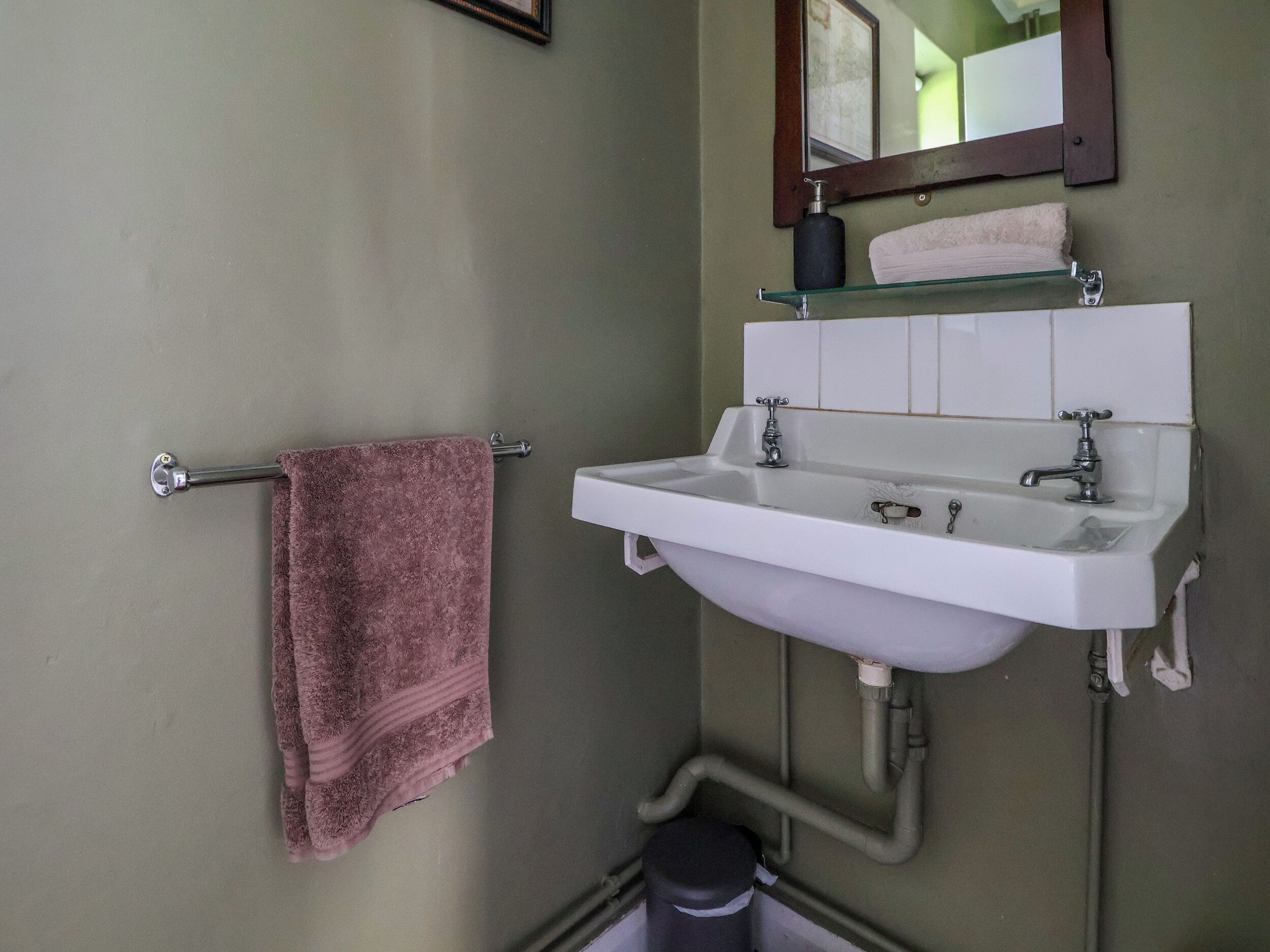 A bathroom with a white sink, a mirror, and a towel rack.