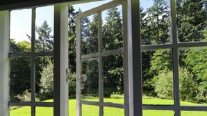A conservatory with a view of a green lawn and trees. - New Hall (Wrexham)