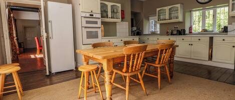 A kitchen with a wooden table and chairs, white cabinets, and a clock on the wall.