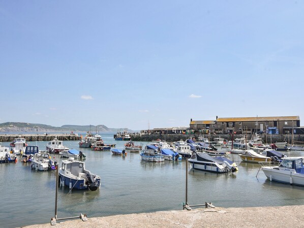 Un port de plaisance où sont amarrés différents types de bateaux, une jetée et un bâtiment sur lequel on peut voir une enseigne.
