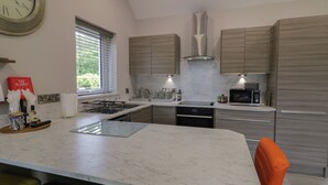 A modern kitchen with a central island, stainless steel appliances, and wooden cabinets. - Mountain View (Limavady)