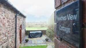 En stenmur med en skylt som visar texten: ”Roaches View Cottage”.