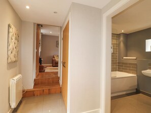 A modern bathroom with a bathtub, a sink, and a shower. There is a wooden staircase leading to another room.