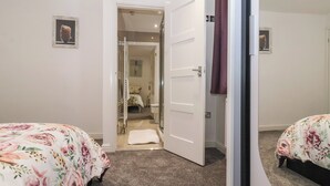 Een slaapkamer met een bed, een deur naar een badkamer en een klein raam.